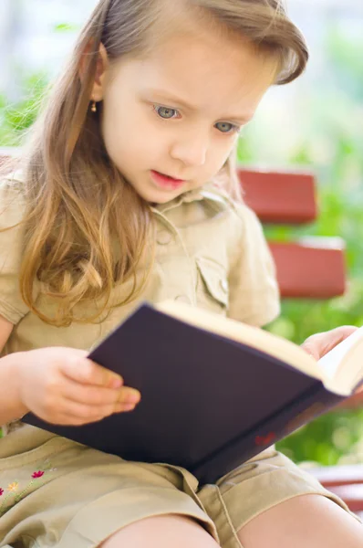 Liten flicka läser en bok — Stockfoto