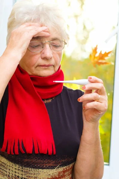 Old woman taking her temperature — Stock Photo, Image