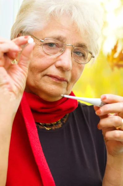 Old woman taking her temperature — Stock Photo, Image