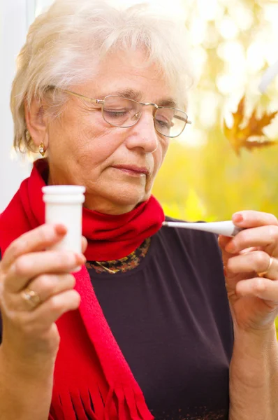 Old woman taking her temperature — Stock Photo, Image