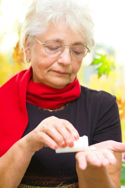 Senior woman holding a pill in her hand — Stock Photo, Image