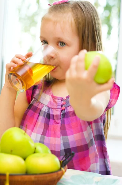 Ребенок держит зеленое яблоко и пьет сок — стоковое фото