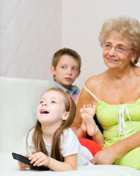Grandmother with her grandchildren are watching TV — Stock Photo, Image
