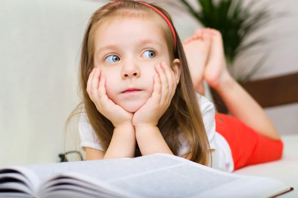 Dítě je čtení knihy vleže na gauči — Stockfoto