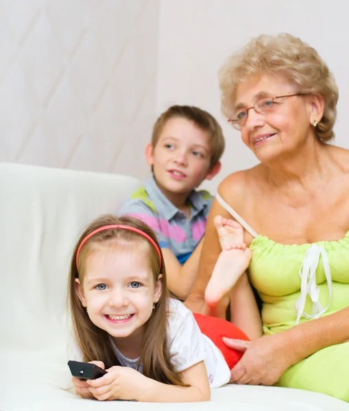 Бабушка с внуками смотрят телевизор — стоковое фото