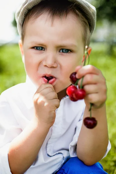 Мальчик ест вкусные вишни — стоковое фото