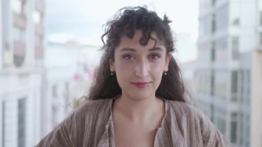 Güzel görünümlü, çok ırklı esmer, zarif ve yavaş çekimde kameraya bakan genç bir kadının yakın plan portresi. Günlük hayat, moda, güzellik. Kadın portreleri. Kadın portreleri. 4k görüntü