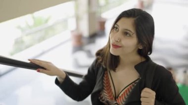 Genç ve çekici bir kadın alışveriş merkezinde yürüyen merdiven kullanıyor. Beyaz kadın, yürüyen merdivende şık kıyafetler giyiyor. Gülümseyerek günün tadını çıkarıyorum. Alışverişten mutlu