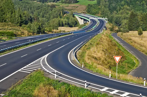 Access road to the highway between forests in the landscape — Stock Photo, Image