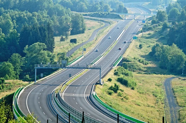 La carretera entre bosques en el paisaje — Foto de Stock