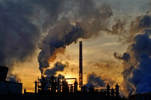 Chaminés e fumaça escura sobre a fábrica de produtos químicos ao pôr do sol — Fotografia de Stock