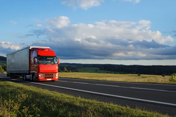 yol ve hareketli kırmızı kamyon ile kırsal manzara