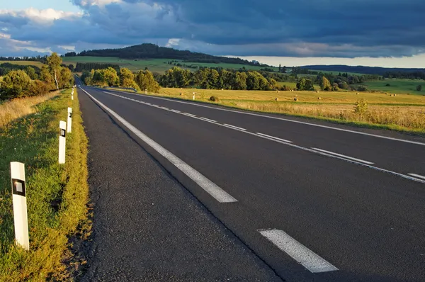 アスファルト道路の水平線に向かってフィールドを介して — ストック写真