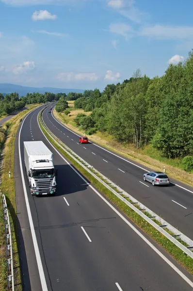 Highway passing through the countryside, truck and passenger cars — Stock Photo, Image