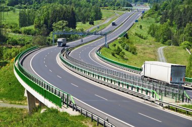 The highway between woods, electronic toll gates, three moving trucks clipart