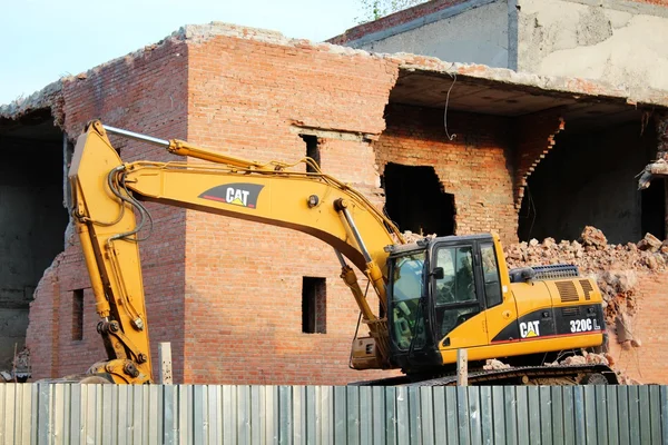 Amarelo escavadeira e tijolo edifício destruição — Fotografia de Stock