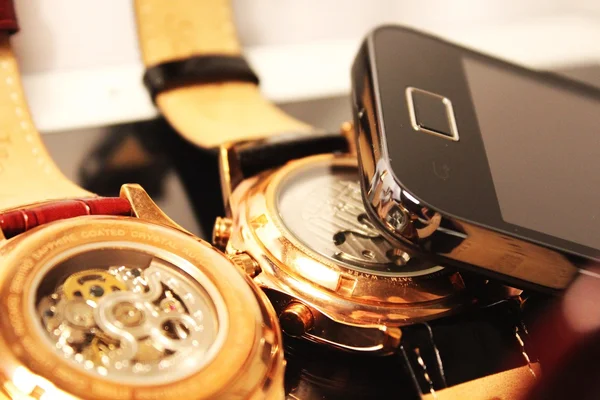 Goldene Armbanduhren und Handy — Stockfoto