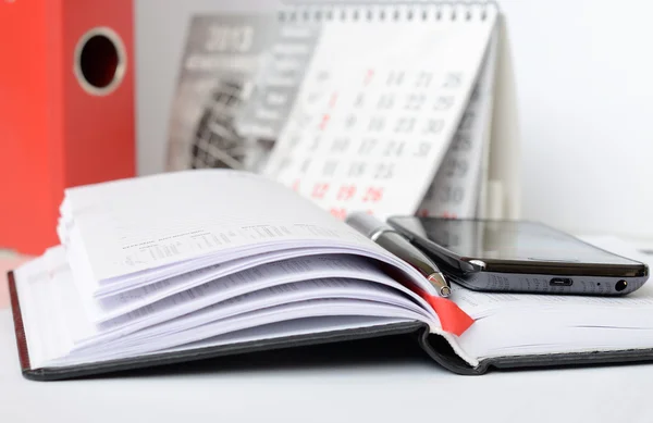 Telefone e caneta em um caderno — Fotografia de Stock