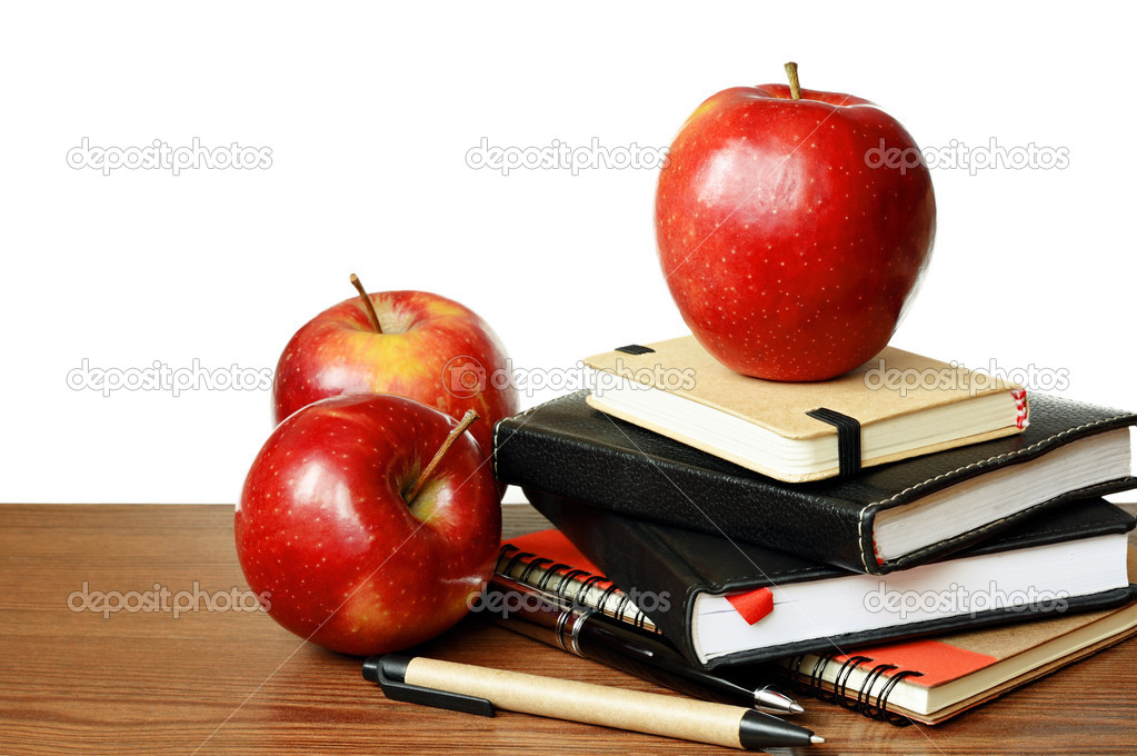 Notebooks, pens and apples on a table