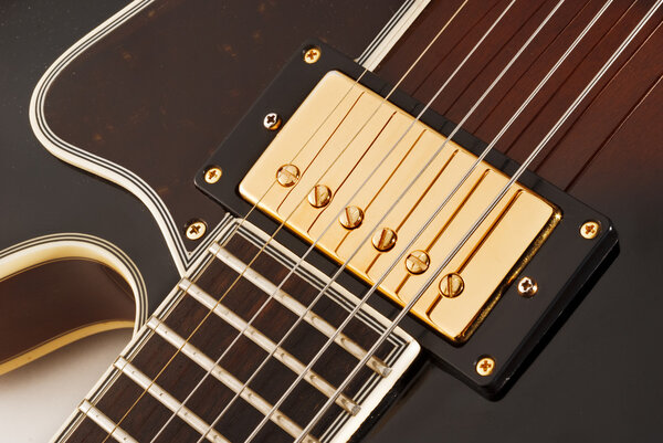 Golden covered pick up of an electric guitar, close up