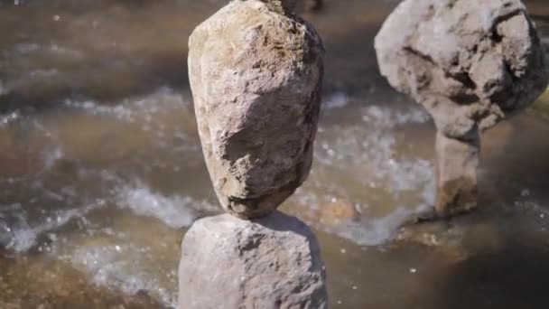 El concepto de equilibrio. Una piedra se equilibra sobre otra piedra sobre el fondo de un río de montaña — Vídeos de Stock