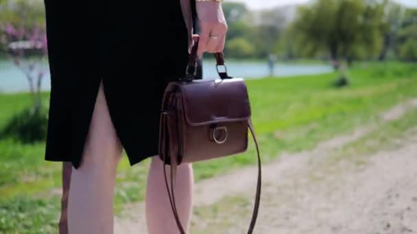 Nahaufnahme eines Mädchens mit einer Handtasche in der Hand im Sommer draußen an einem sonnigen Tag — Stockvideo