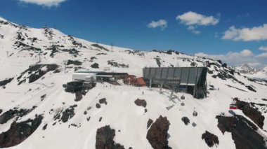 Teleferiğin üzerinden, fünyelerle kar kaplı Elbrus Dağı 'na uçan bir hava aracı. Rusya, Elbrus Bölgesi - 14 Mayıs 2021