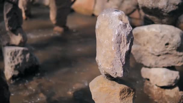 Der Stein steht auf einem Stein und balanciert im Bett eines Gebirgsflusses mit starker Strömung. Eine Münze auf einem Stein. — Stockvideo