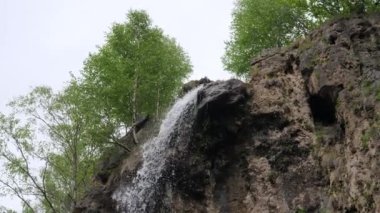 Dağlarda küçük bir şelale küçük bir dağ nehrine akar. 4K