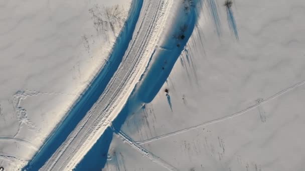 Luchtfoto naar beneden 4k uitzicht op de winter tractor vrijgemaakt weg. Weg tussen de sneeuw. — Stockvideo