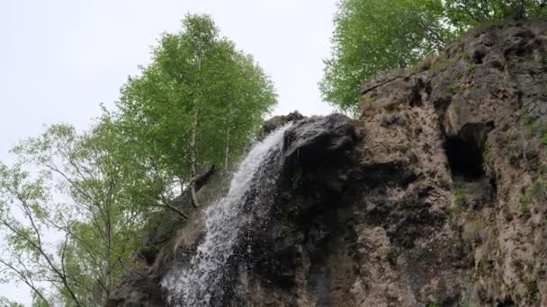 Una pequeña cascada en las montañas desemboca en un pequeño río de montaña. 4K — Vídeo de stock