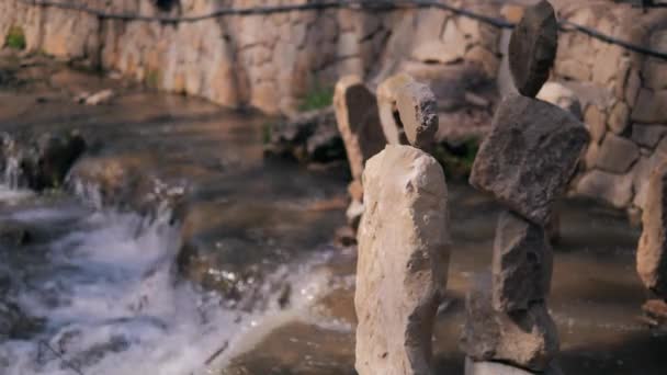 Escultura de piedras balanceándose una encima de la otra en la ladera de un río de montaña con una fuerte corriente — Vídeos de Stock