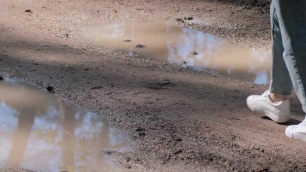 Close-up de pés de homem andando em tênis limpos brancos através de lama entre poça — Vídeo de Stock