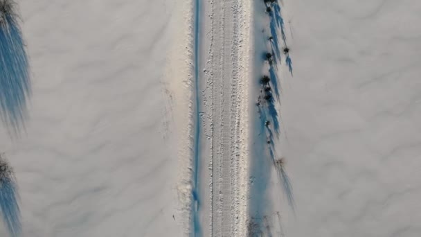 Aerial Top Down Flyover Shot zimowej drogi transportowej na obszarach wiejskich wśród śniegu drifts — Wideo stockowe