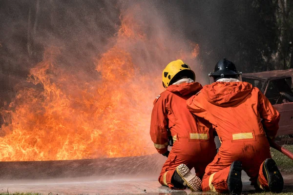 İtfaiyeci, eğitim merkezindeki yangını söndürmek için su sıkıyor..