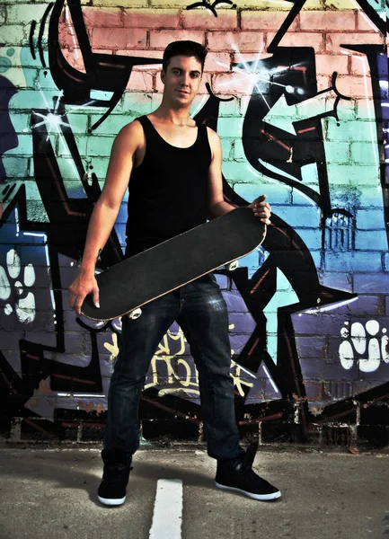 Junger Mann posiert mit seinem Skateboard — Stockfoto