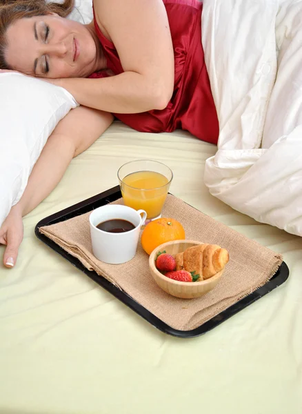 Donna che dorme nel suo letto con la colazione al suo fianco — Stockfoto