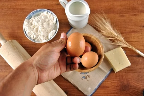 Hand picking eggs and flour — Stock Photo, Image