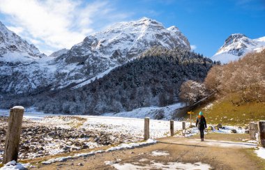 Person walking in the Artiga de Lin, in the Aran valley, located in the Catalan Pyrenees in Spain. Cold and snowy days of the first days of winter. clipart