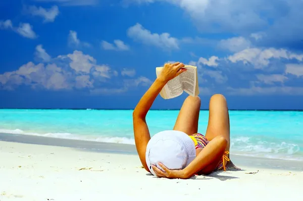Unga kvinnor är att läsa på stranden coral — Stockfoto