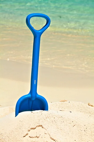 Barnens spade ligger på en strand — Stockfoto