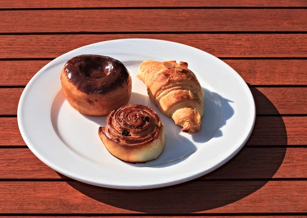 Croissant, donut in chocolade en roll met rozijnen — Stockfoto