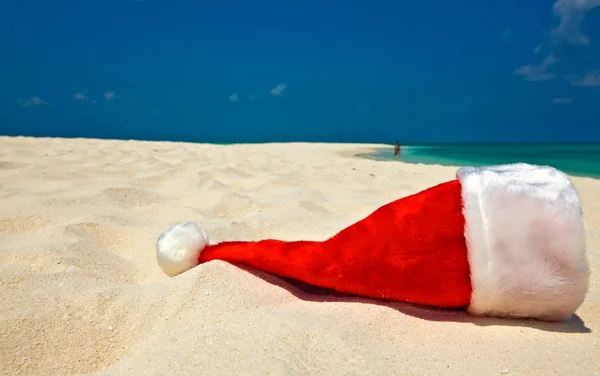 Kerstman hoed is op een strand — Stockfoto