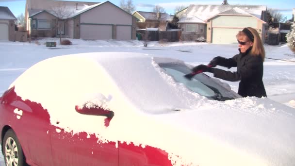 Женщина убирает снег с машины — стоковое видео