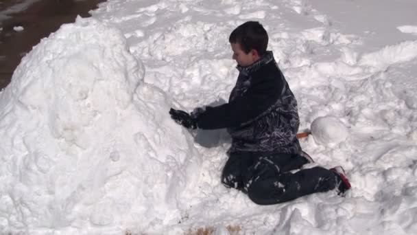 Jongen verpakking sneeuw op snowman — Stockvideo