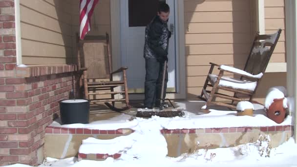 Chico barriendo nieve desde el porche — Vídeos de Stock