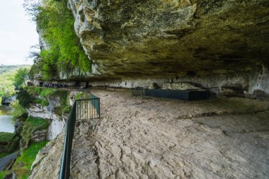 The Roque Saint-Christophe troglodytic villageis a big rock formation with Rock shelters at the river Vezere in the Dordogne, southwest France clipart