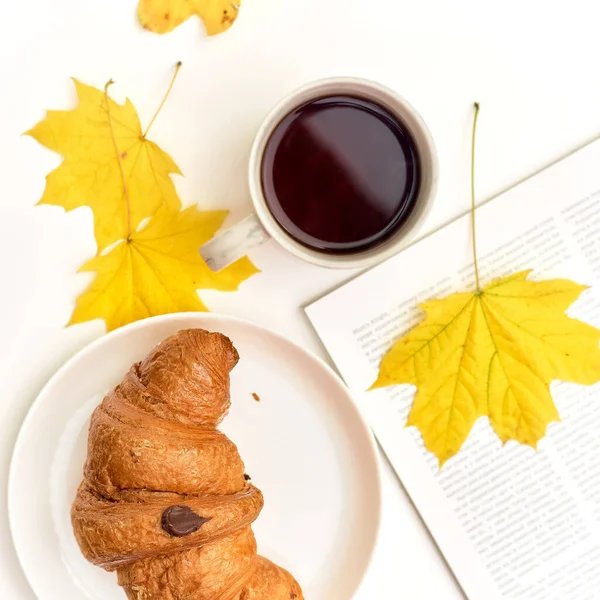 Croissant with coffee on the background of a heap of books. Student eating breakfast — Stock Photo, Image