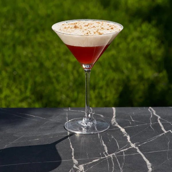 Red cocktail with froth and shaving on restaurant table — Stockfoto