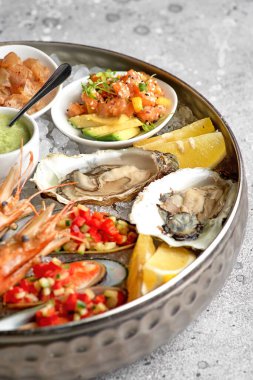 Açık istiridye, çiğ midye ve havyarlı metal tepsi. Deniz ürünleri çeşitleri. Taş zeminde. Metin için boş alan.